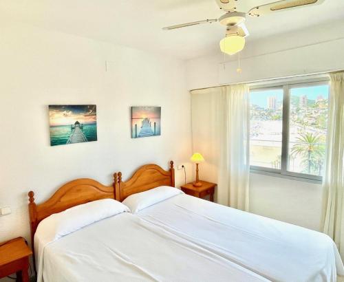 1 dormitorio con 1 cama con sábanas blancas y ventana en Apartamentos Ulia, en Benidorm