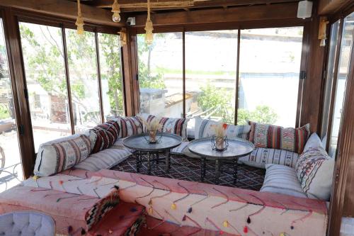 a living room with couches and tables and windows at Simera in Cappadocia - Special Class - Best View Rooftop in Uchisar