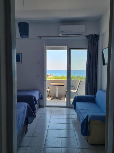 a room with two beds and a table and a balcony at Lyttos in Tsoutsouros