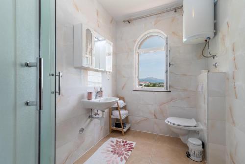 baño con lavabo y aseo y ventana en A3 - seafront apt with balcony 1 min to beach en Trogir