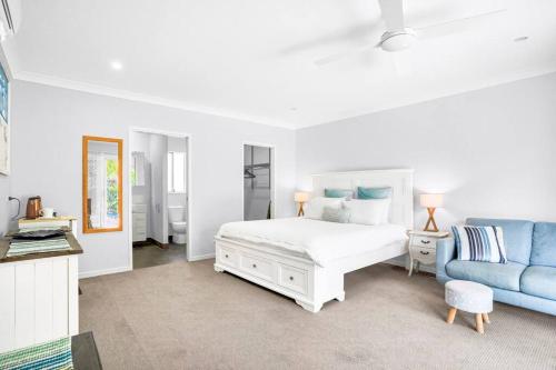a white bedroom with a bed and a blue couch at SeaBreeze Studios ( Room 1 ) - Palm Cove in Palm Cove