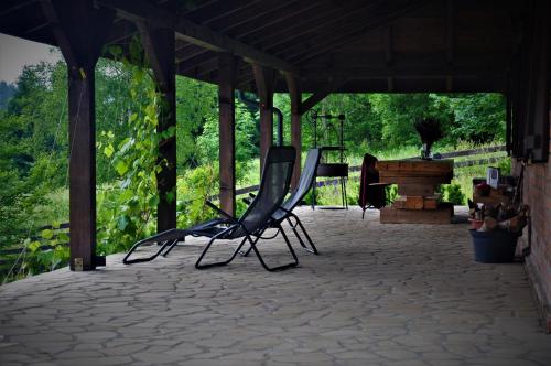 two black chairs sitting on a patio with a grill at Chata nad Dziką Orlicą z jacuzzi in Poniatów