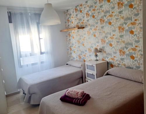 a bedroom with two beds and a wall with flowers at Beatiful and full-equipped flat in the city center in Ceuta