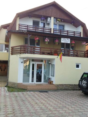 a large white building with a balcony on top of it at Pensiunea Krystinne in Hunedoara