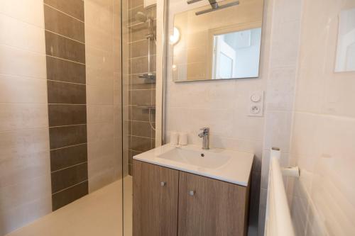 a bathroom with a sink and a mirror and a shower at Le Kador, appartement avec vue sur mer in Crozon