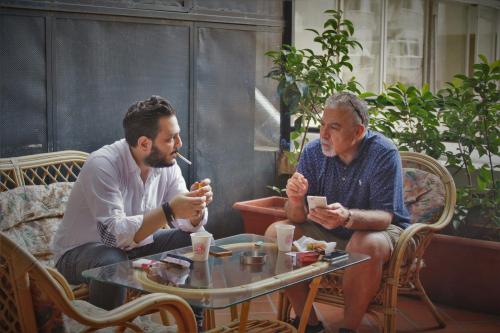 two men sitting at a table eating food at Hamra Urban Gardens in Beirut