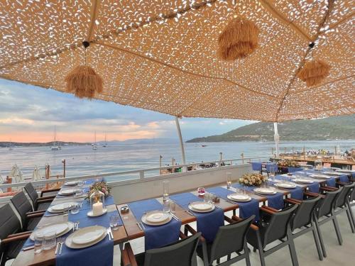 a long table with blue chairs and a view of the ocean at Lavinya Otel in Golturkbuku