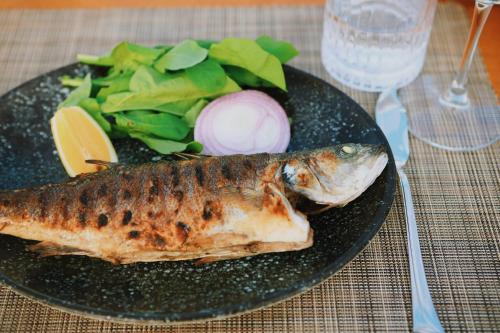 a plate with a fish and salad on a table at Lavinya Otel in Golturkbuku