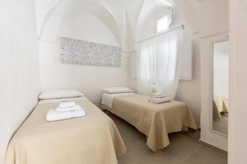 Dieses weiße Zimmer verfügt über 2 Betten und ein Fenster. in der Unterkunft Vico dei Mille by BarbarHouse in Tuglie