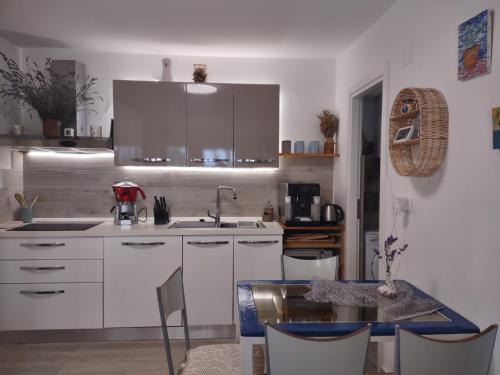 a kitchen with white cabinets and a dining table at Stone Villa Hvar Ana Nikola Beach Park and Sea View in Jelsa