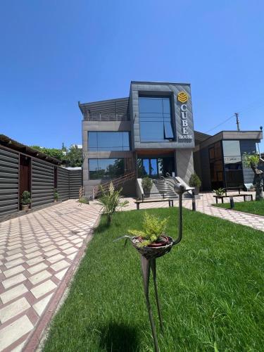 a house with a bird statue in the grass at Cube House Osh in Osh