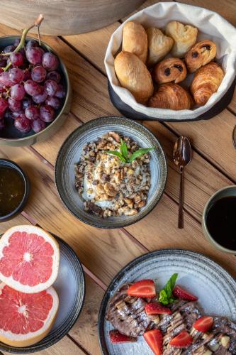 a wooden table topped with plates of food and bread at Serra Exclusive Suites in Akrotiri