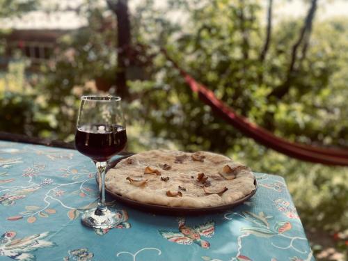 a pizza and a glass of wine on a table at Bali Glamping in Ambrolauri