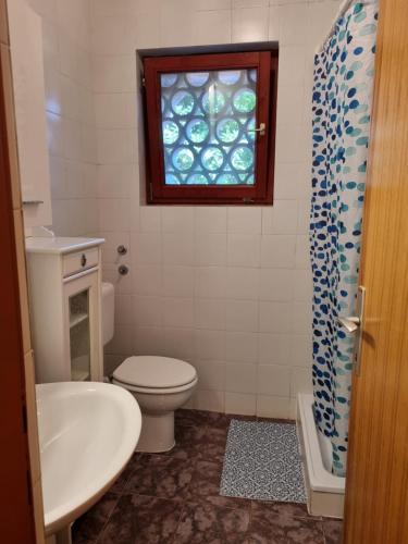 a bathroom with a toilet and a sink and a window at Apartments Jelena in Peroj
