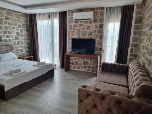 a bedroom with a bed and a couch and a tv at Agape Rose in Herceg-Novi