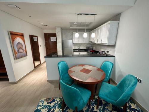 a kitchen with a table and some blue chairs at BANIYAS PLAZA HOTEL APARTMENTS in Abu Dhabi