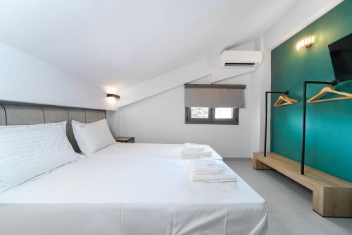 1 dormitorio con cama blanca y pared verde en Aerino Luxury Villas en Chrysi Ammoudia