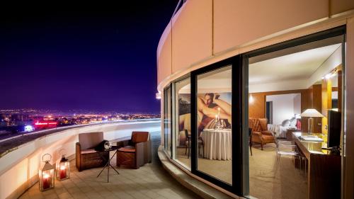 a building with a view of a city at night at Enea Hotel Aprilia in Aprilia