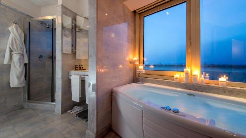 een badkamer met een bad, een raam en kaarsen bij Enea Hotel Aprilia in Aprilia