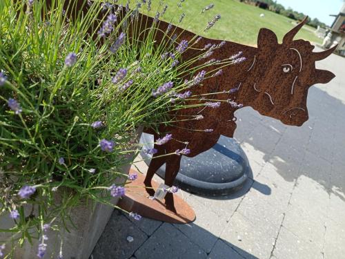 a statue of a cow sitting next to a plant at Gîte Ferme d'hurtaux in Froid-Chapelle