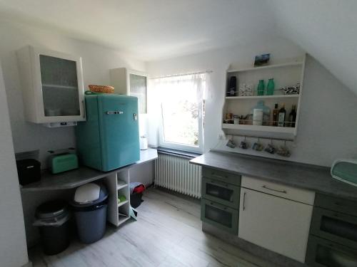 eine Küche mit einem blauen Kühlschrank und einem Fenster in der Unterkunft Ferienwohnung "Pipistrello" mit Minizoo in Wursterheide