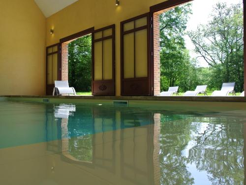 a swimming pool with white chairs in a house at Hameau de la Fausse Sauge in Mézilles