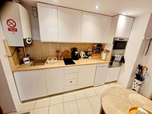 a small kitchen with white cabinets and a sink at Room4U mieszkania w centrum in Szklarska Poręba