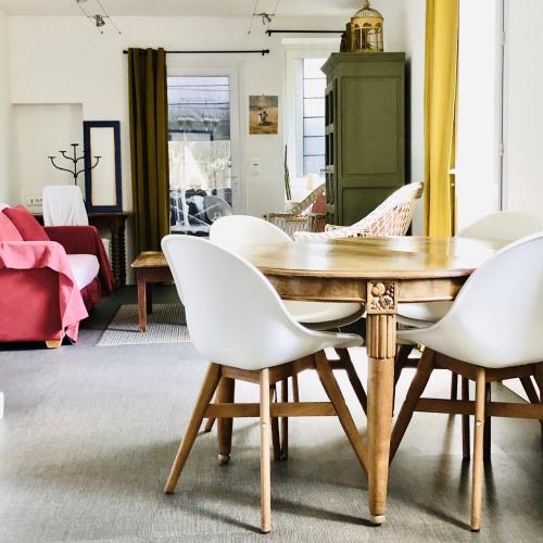 une salle à manger avec une table en bois et des chaises blanches dans l'établissement Charmante maison entre Marché et Tourelles, à Pornichet