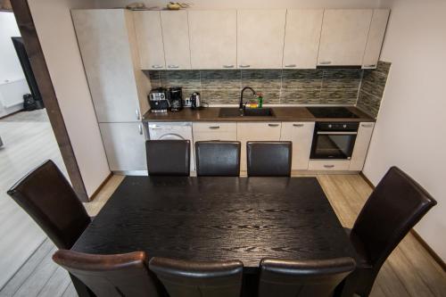 a kitchen with a black table with chairs and a sink at Casa Arcadia 2 piscina,ciubar in Merei