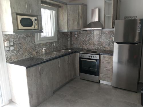 a kitchen with a stainless steel refrigerator and a microwave at Perivoli Tessas' in Parga