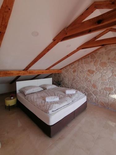 a bed in a room with a stone wall at Sky apartment, Island Rab in Rab