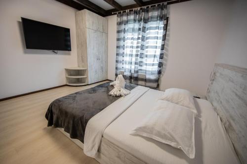 a bedroom with a large bed and a flat screen tv at Casa Arcadia 2 piscina,ciubar in Merei