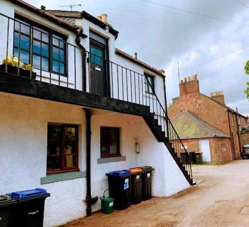 a building with two trash cans in front of it at Burnside Cottages in Fettercairn