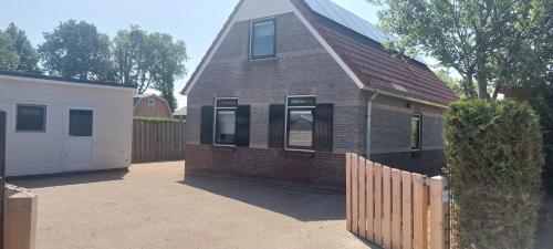 a brick house with a fence and a white garage at hûske twa in Oudwoude