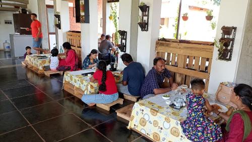 a group of people sitting at tables in a room at Wow Farm House & Resort near Pondicherry in Auroville