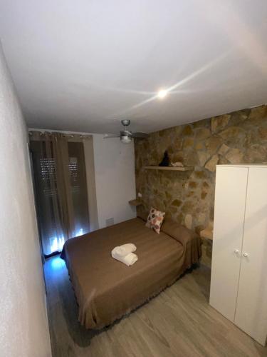 a bedroom with a bed and a stone wall at Casita en el Tajo in Setenil