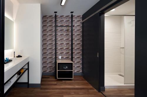 a bathroom with a brick wall and a black door at Aloft Orlando International Drive in Orlando