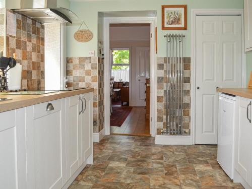 a kitchen with white cabinets and a tile floor at Two Chimneys in Keswick