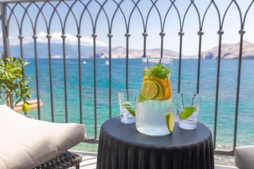 een tafel met twee glazen water en uitzicht op de oceaan bij Seafront Baska Apartment in Baška