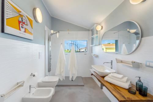 a white bathroom with two sinks and a mirror at La Pimpinella in Su Forti