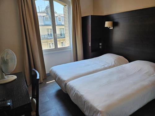 two beds in a hotel room with a window at Hôtel Bellevue et du Chariot d'Or in Paris