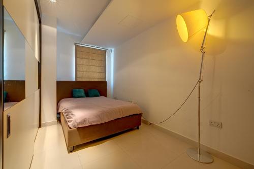 1 dormitorio con 1 cama y lámpara de pie en Exquisite Seafront Apart in Spinola Bay St Julians en Paceville