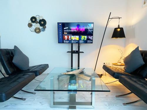 sala de estar con mesa de cristal y TV en FeWo Sonnenlay - Apartments an der Mosel, en Brauneberg