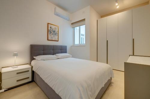 a white bedroom with a bed and a window at Luxury Maisonette in a Tranquil and Central Area in St. Julianʼs
