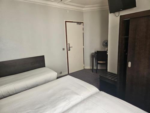 a room with two beds and a desk and a mirror at Hôtel Bellevue et du Chariot d'Or in Paris
