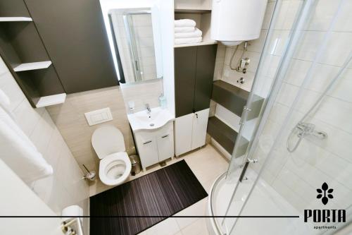 a small bathroom with a toilet and a shower at Porta Apartman Sarajevo in Sarajevo