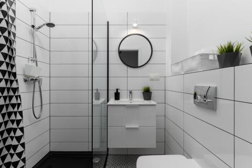 La salle de bains blanche est pourvue d'un lavabo et d'un miroir. dans l'établissement Lagunowe Zacisze, à Zarzecze
