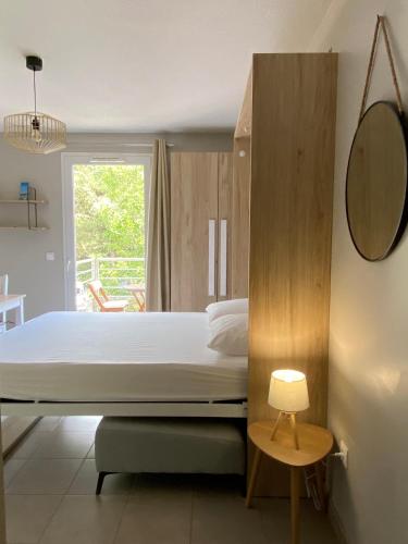 une chambre avec un lit et un miroir dans l'établissement Les locations Cinaureva « Le petit nid de l'Argentière », à La Londe-les-Maures