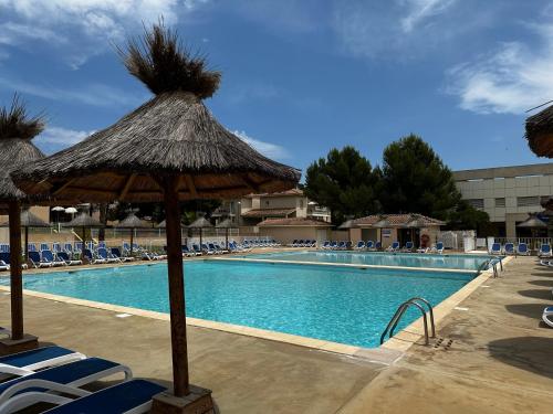 - une piscine avec des chaises et un parasol dans l'établissement Les locations Cinaureva « Le petit nid de l'Argentière », à La Londe-les-Maures