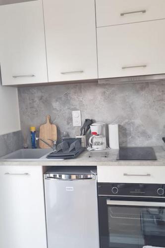 une cuisine avec des armoires blanches, un évier et une cuisinière dans l'établissement Superbe studio à 8mn en voiture de la plage, à Linxe